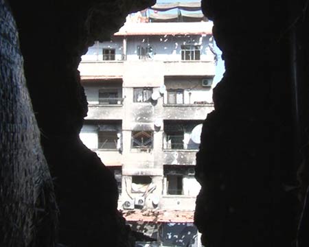 أحد الابنية المتضررة من فجوة احدثتها قذيفة الجيش العربي السوري يتجه لاستكمال طوق دمشق